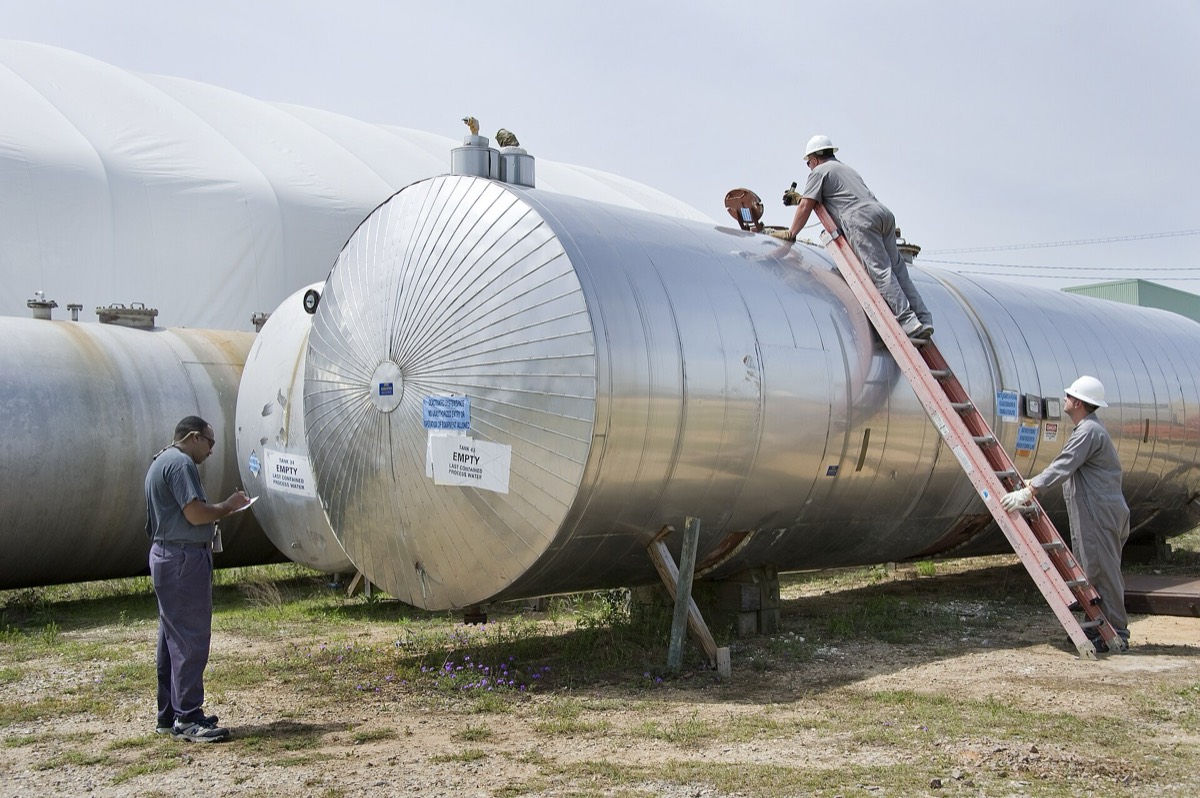 Workers inspecting industrial chemical storage tanks